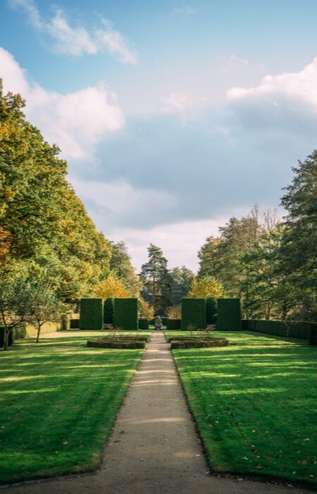 A vertical shot of the Hoetger Park covered in greenery under a cloudy sky in sunlight in Dortmund, Germany